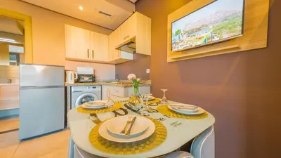 a kitchen with a table and a tv on the wall at Atlas-Résidence by Rent-Inn in Rabat