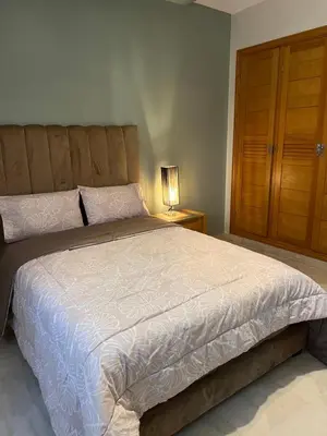a bedroom with a large bed and a wooden cabinet at PERLA NOUACEUR AéROPORT MOHAMMED V in Nouaceur