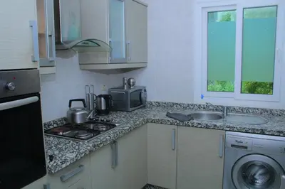 a kitchen with a stove top oven next to a sink at MOHAMMEDIA Residence KAWTAR in Mohammedia