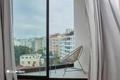 a chair sitting on a balcony with a view of a city at Stayhere Casablanca - Palmier - Executive Residence in Casablanca