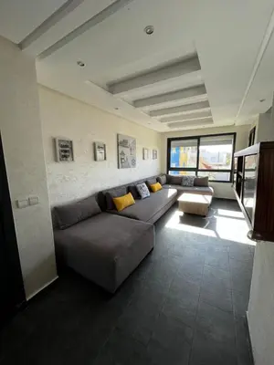 a living room with a couch and a table at Appartement front de mer avec piscine en face des plages privées in Dar Bouazza
