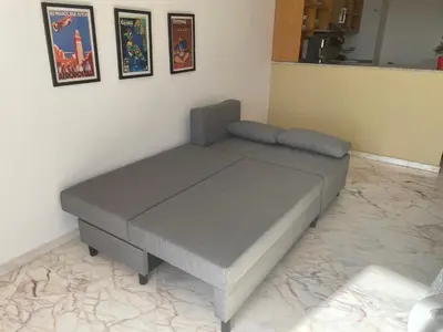 a gray bed in a room with pictures on the wall at Airport to Comme à la maison 2 in Derroua