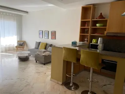 a kitchen and living room with a counter and chairs at Airport to Comme à la maison 2 in Derroua