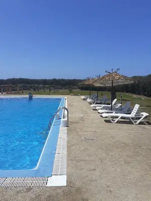 a row of lounge chairs and umbrellas next to a pool at Atlantic Vacation villa in Dar Oulad Hajj Kassem