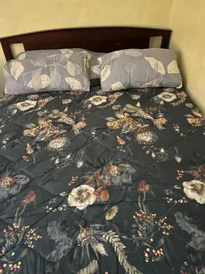 a bed with a black floral comforter and two pillows at Atlantic Vacation villa in Dar Oulad Hajj Kassem