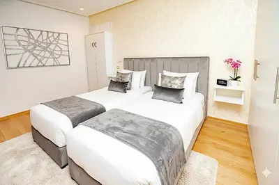 two beds in a room with white walls and wood floors at Family Aparthotel in Casablanca