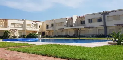 a swimming pool in front of a building at Bel appartement Savannah Beach in Sidi Rahal