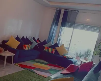 a living room with a blue couch with colorful pillows at Appartement la Siesta beach resort Mohammedia in Mohammedia