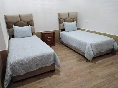 two beds sitting in a room with wooden floors at Appartement bien situé Dahomey city . Bahia beach in Bouznika