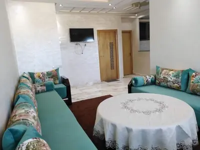 a living room with two blue couches and a table at Appartement bien situé Dahomey city . Bahia beach in Bouznika