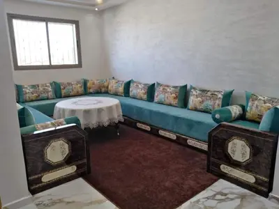 a living room with a blue couch and a table at Appartement bien situé Dahomey city . Bahia beach in Bouznika