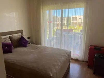 a bedroom with a bed with purple pillows and a window at Bel appart à Hacienda Beach Sidi Rahal in Sidi Rahal