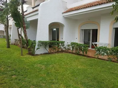a white house with a yard with grass and a house at Sidi Rahal , Residence Garden Beach 2 in Sidi Rahal