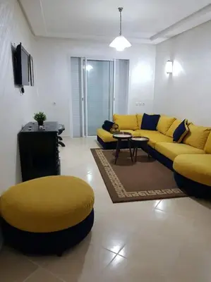 a living room with a yellow couch and a table at Sidi Rahal , Residence Garden Beach 2 in Sidi Rahal