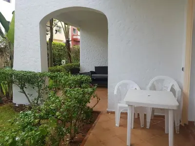 a white table and two white chairs in a courtyard at Sidi Rahal , Residence Garden Beach 2 in Sidi Rahal