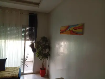 a living room with a plant and a painting on the wall at luxu appart siesta beach resort in Mohammedia