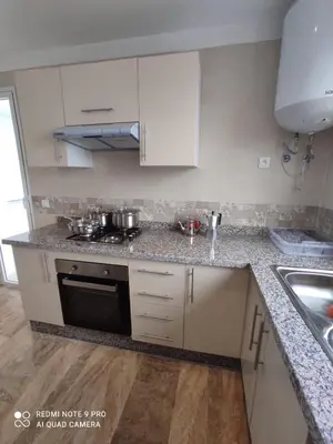 a kitchen with white cabinets and a stove top oven at Apartment place italie in Rabat