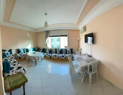 a living room with a couch and a table at Bel Appartement au cœur de BOUZNIKA in Bouznika