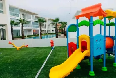 a playground with a slide in a yard at Appartement à louer dans une résidence balnéaire 3 piscines - RAMOFLORES Sidi Rahal in Sidi Rahal
