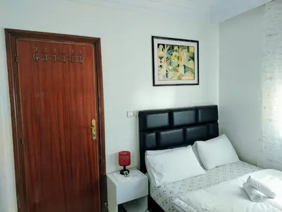 a bedroom with a bed and a wooden door at Appartement 11 Casa Voyageurs in Casablanca