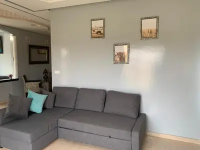 a living room with a gray couch against a white wall at American Farm Villa Grand Casablanca/El Jadida in Zaouia Sidi Bou Azza