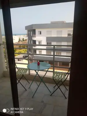 a table and chairs on a balcony with a building at Belfakih in Beni Brour