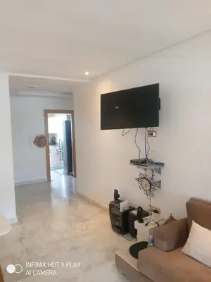 a living room with a couch and a flat screen tv on the wall at Belfakih in Beni Brour