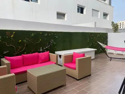 a patio with pink couch and chairs and a table at Les Jardins de l'Oasis - 2 rooms in Casablanca