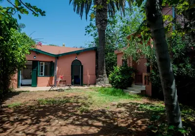 a house with a palm tree in front of it at Charmante Maison 2ch et Bungalow 2ch au Coeur de l'Oasis in Casablanca