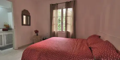 a bedroom with a red bed and a window at Charmante Maison 2ch et Bungalow 2ch au Coeur de l'Oasis in Casablanca
