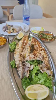 a plate of food with fish and lettuce on a table at appartement de luxe front mer à DAR BOUAAZA in Dar Bouazza
