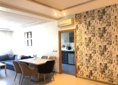 a living room with a table and a kitchen at Bright and Comfortable Stay by Stade Mohammed V in Casablanca