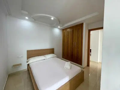 a bedroom with a white bed and a wooden cabinet at Cozy Apartment in Rabat