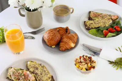 a white table with plates of food and a glass of orange juice at Stayhere Casablanca - Gauthier 2 - Contemporary Residence in Casablanca