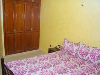 a bedroom with a bed and a wooden cabinet at Yasmine Appartements in Temara