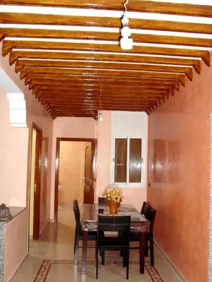 a dining room with a wooden ceiling and a table and chairs at Yasmine Appartements in Temara