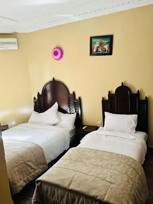 a hotel room with two beds and a pink clock on the wall at HOTEL AL MAMOUN in Casablanca