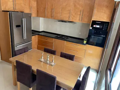a kitchen with a wooden table with chairs and a refrigerator at Apparemment à mohammadia in Mohammedia