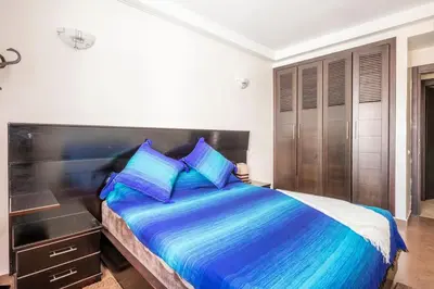 a bedroom with a large bed with a wooden headboard at Layover Guest House Apartment & parking Rabat Agdal City Center in Rabat