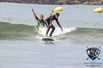 two men riding a wave on a surfboard in the ocean at Appartement de standing vue sur mer à Mohammedia in Mohammedia