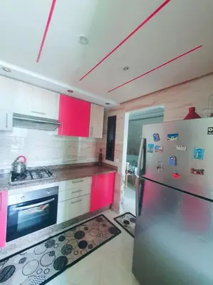 a kitchen with a stainless steel refrigerator and red cabinets at Appartement sidi rahal in Berrechid