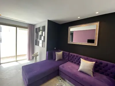 a living room with a purple couch and a mirror at CORNICHE CASABLANCA - VINTAGE F2 NEUF in Casablanca