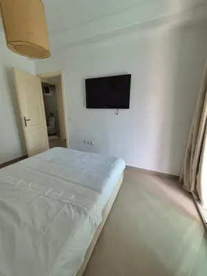 a white bedroom with a bed and a flat screen tv at My Cosy Place Rabat - Cosy Home Wifak Temara in Temara