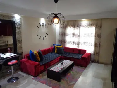 a living room with a red couch and a clock on the wall at Zen Home in Casablanca