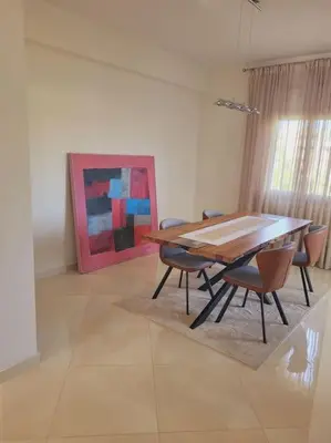 a dining room with a table and chairs and a painting at Luxury in the heart of Hay Riad in Rabat