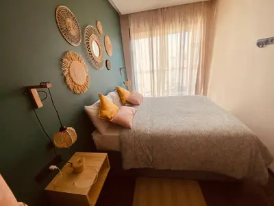 a bedroom with a bed and a window and a table at Appartement Cosy et chaleureux - Casablanca centre in Casablanca