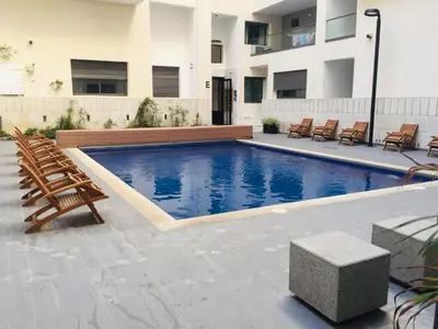 a swimming pool with chairs and a building at Miramare Cosy appartement pied dans l'eau avec piscine in Mohammedia