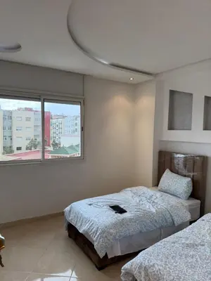 a bedroom with two beds and a large window at Appt front la mer in Rabat