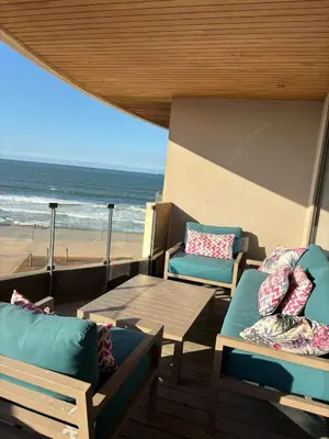 a patio with chairs and a table and the beach at Marina Casa Del Mar - Amazing Sea & Mosque views in Casablanca