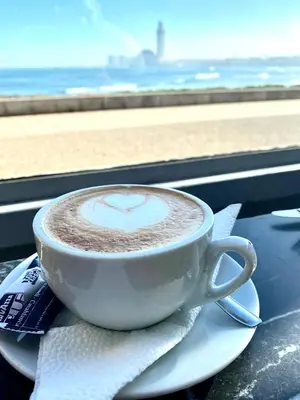 a cup of cappuccino on a plate with a view of the beach at appartement en plein centre de casablanca in Casablanca